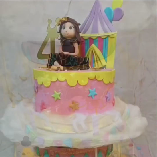 Rotating Carnival theme kids birthday cake with a girl figurine, showcasing an eggless cakes design for a theme cake Noida.