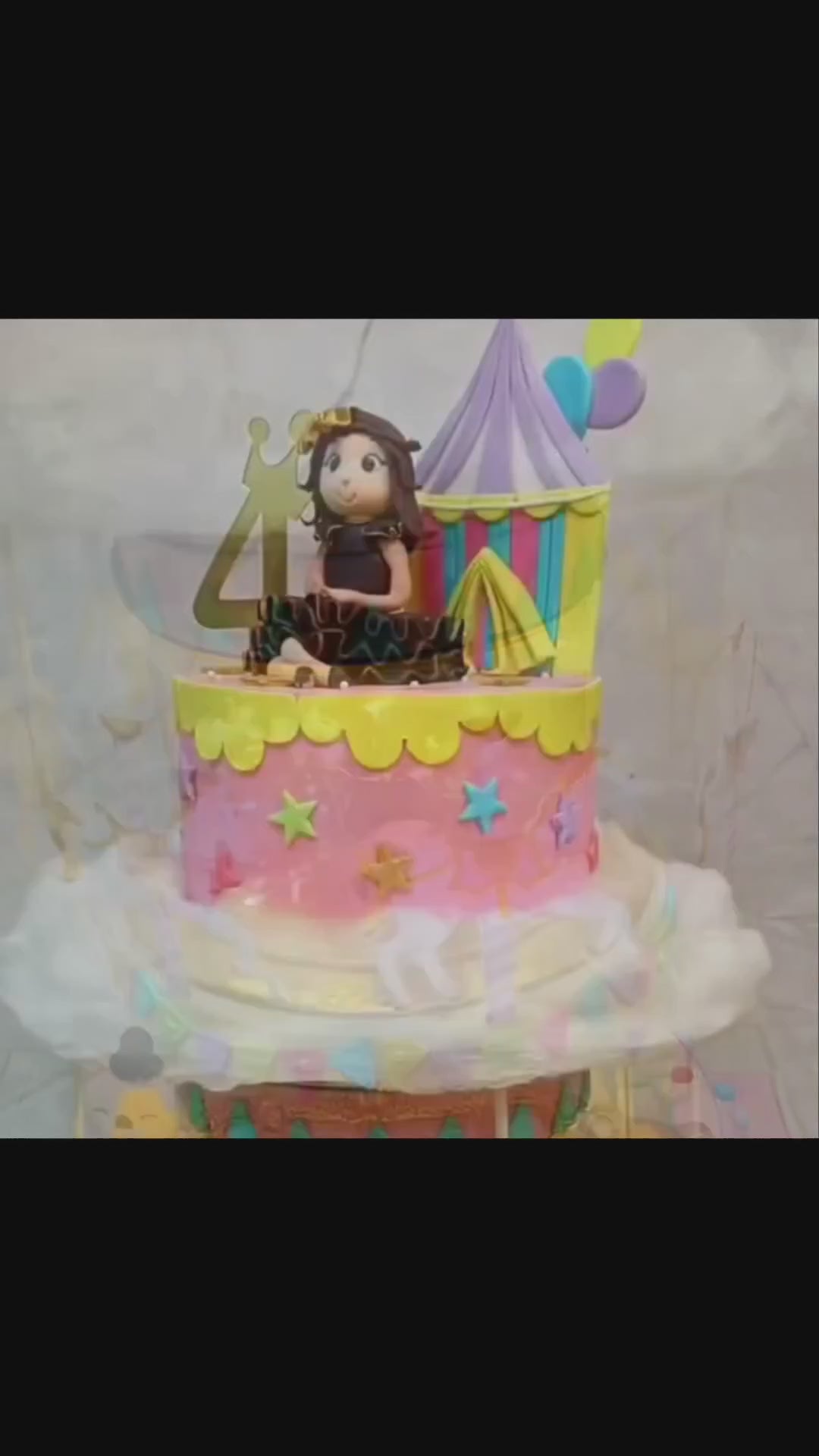 Rotating Carnival theme kids birthday cake with a girl figurine, showcasing an eggless cakes design for a theme cake Noida.