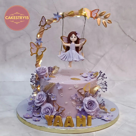 Princess fairy swinging themed eggless kids birthday cake with lavender roses and butterflies by Cakestry15, premium theme cake Noida.