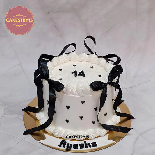 Ribbon bow Black Forest birthday cake with an elegant white icing finish, heart patterns and personalised birthday details.