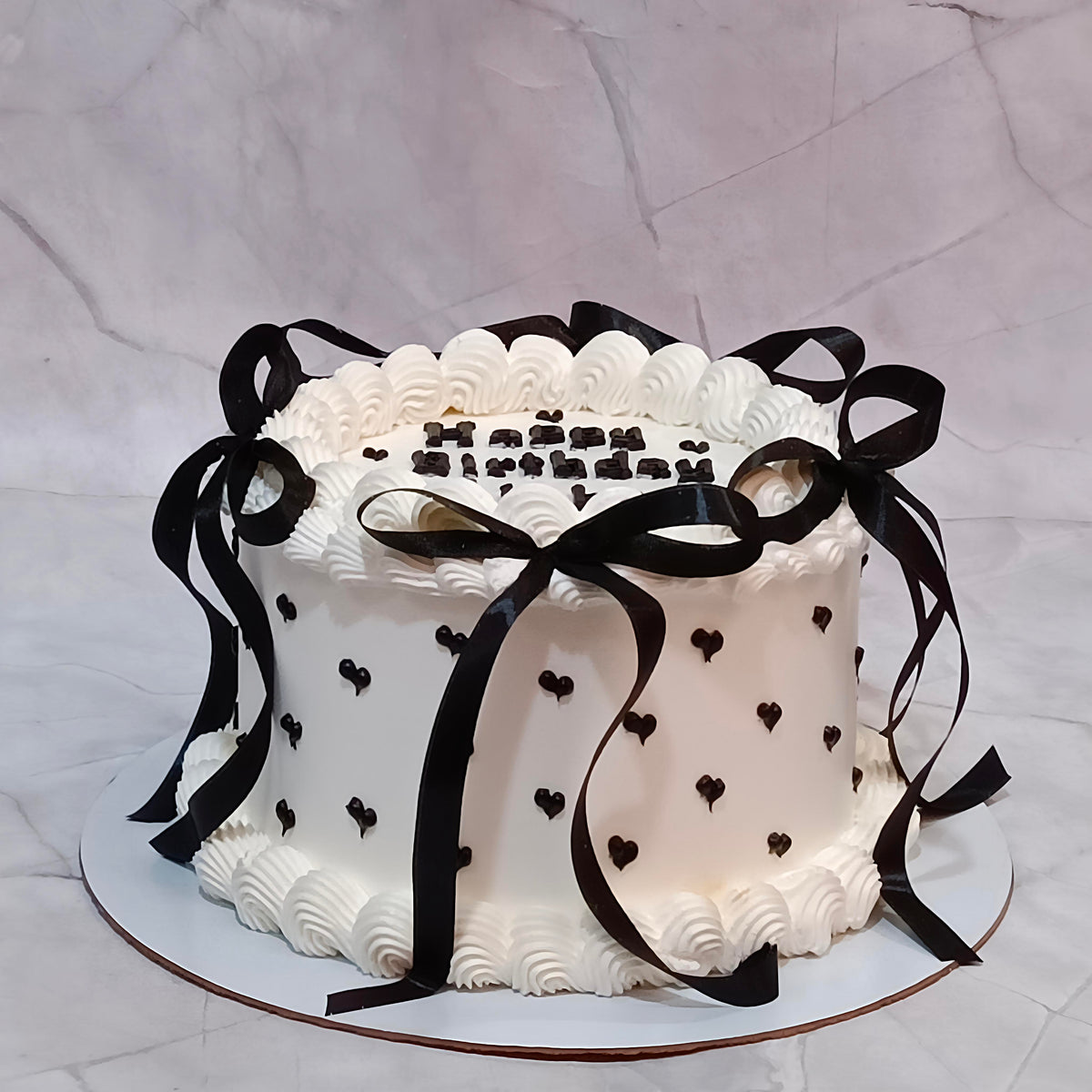 - Black Forest  birthday cake featuring bow-shaped ribbon details all around, heart patterns and personalised name and age.