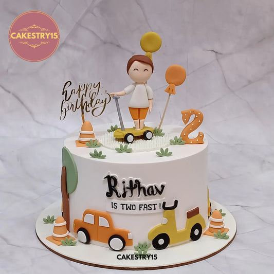 Rithav’s 1.5kg pineapple car theme cake with boy figurine, tricycle, cars, trees, and balloons from Cakestry15 Noida