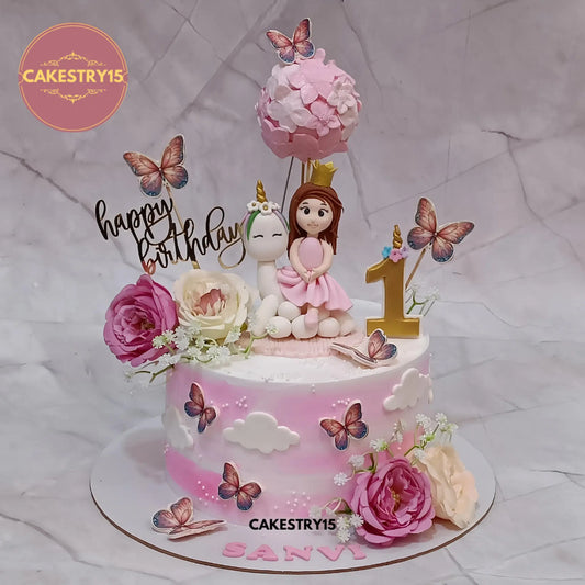 1.5kg choco butterscotch unicorn cake for Sanvi’s 1st birthday with girl topper, air balloon, faux roses, and butterflies by Cakestry15 Noida