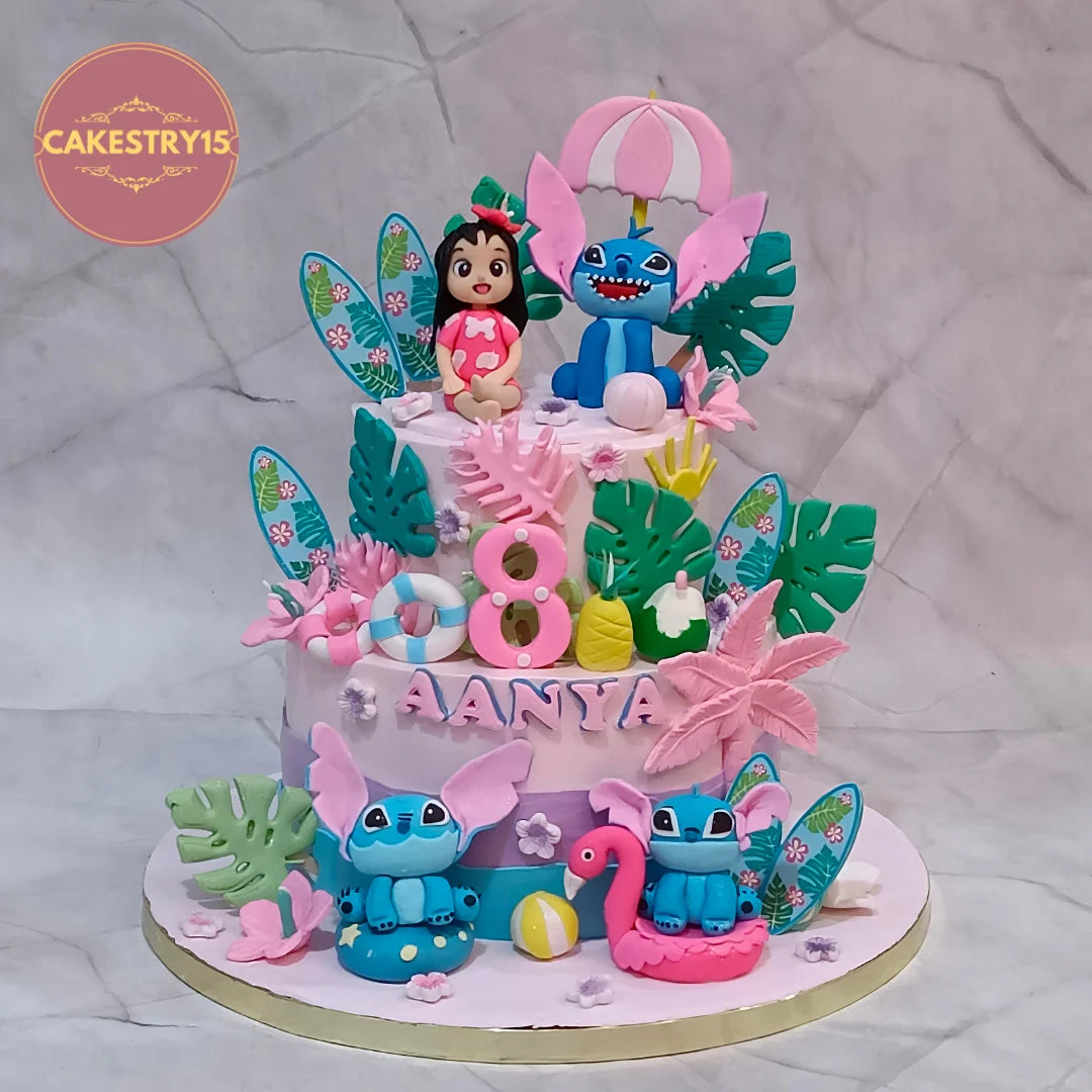 Stitch and Moana kids birthday cake with blue Stitch figures, pink flamingos, palm leaves and a pink umbrella topper.