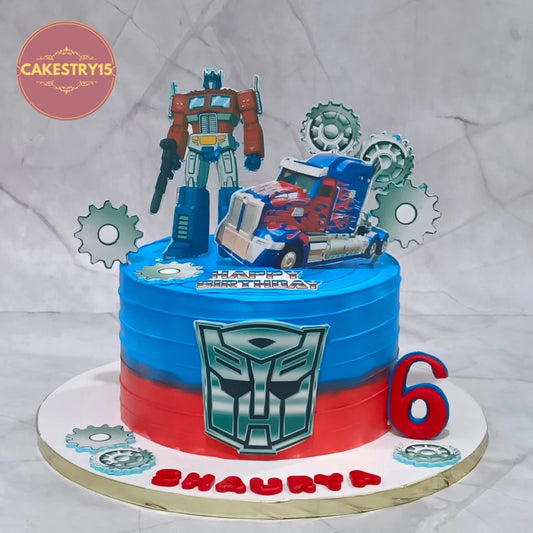 Premium eggless Transformers kids birthday cake with Optimus Prime, blue and red gradient design, and Autobot emblem, a custom theme cake in Noida for a 6th birthday celebration.