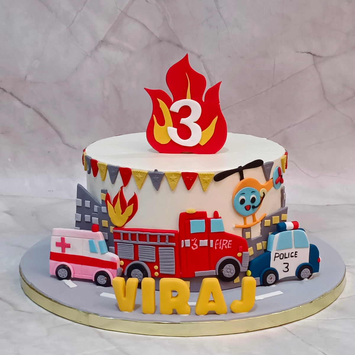 Vehicle theme kids birthday cake with fire brigade, ambulance and police car, available as a theme cake Noida from an eggless cakes bakery.